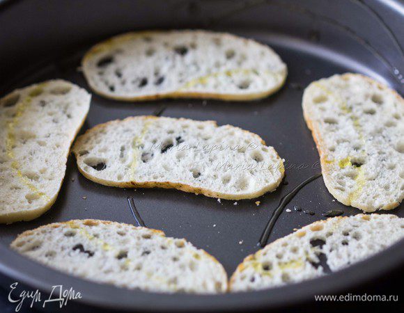 Приготовим гренки. Можно использовать обычные толстые ломтики багета, мне захотелось сделать тоненькие чипсы. Для этого я тонко нарезала багет, выложила в форму, сбрызнула оливковым маслом и поставила в духовку при 200С на 2-3 минуты.