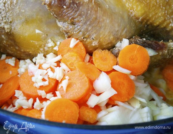Тем временем порезать овощи; лук, морковь и чеснок. Через указанное время добавить овощи к птице и продолжить тушить цесарку.