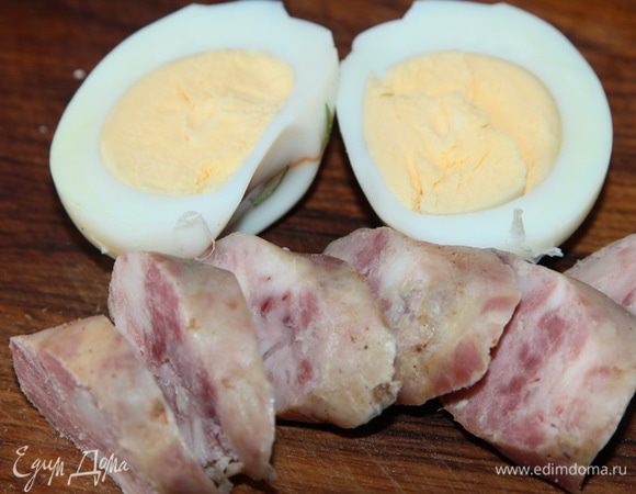 На каждую порцию нарезаем домашние колбаски и кладем по половинке вареного яйца.
