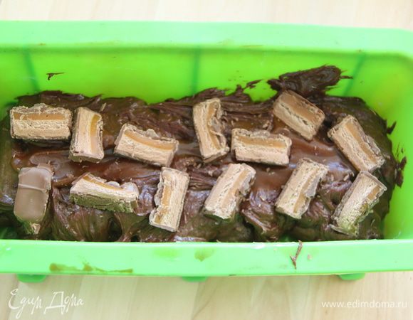 В форму (у меня силиконовая) выложить половину теста, затем немного карамели и половину от общего количества нарезанного батончика.