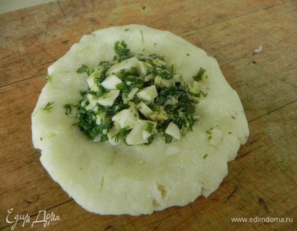 Возьмите небольшое количество картофельного теста, скатайте в шарик, затем придавите, чтобы получилась лепешка, в центр выложите чайную ложку начинки и скрепите края.