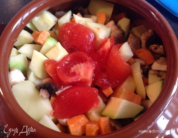 Помидор обдать кипятком, снять кожицу, нарезать на четвертинки. В горшочек сложить мясо, овощи, сверху выложить помидор, и выдавить прессом чеснок. Залить горячим бульоном. Готовить в духовке при 200 градусах 2 часа 30 минут.