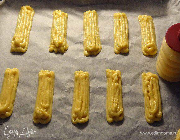 Пирожные удобно формировать с помощью кондитерского шприца с насадкой, но при его отсутствии можно это делать с помощью двух ложек: одной набирать, а другой сталкивать. Я делаю пирожные с помощью маленького кондитерского силиконового шприца со звездообразной насадкой. Конечно, возни с этим больше, но мне очень уж нравится легкая ребристость на готовых эклерах. Пирожные располагать на противне на значительном расстоянии друг от друга!