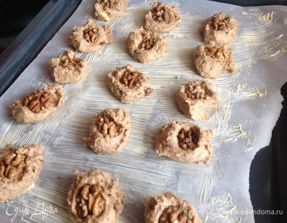 Противень застелите бумагой для выпечки, смажьте маслом. Тесто выложите ложкой на противень и сверху положите половинку грецкого орешка.