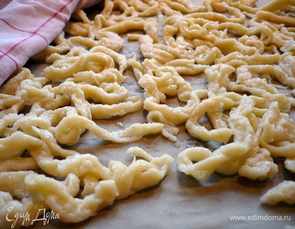 Выкладываем их на сито, промываем холодной водой и выкладываем на противень, застеленный пекарской бумагой. Накрываем сверху влажным полотенцем. Проделываем то же самое с остальным тестом. В лук добавляем сахар и яблочный сок, доводим до кипения и снимаем с огня.  