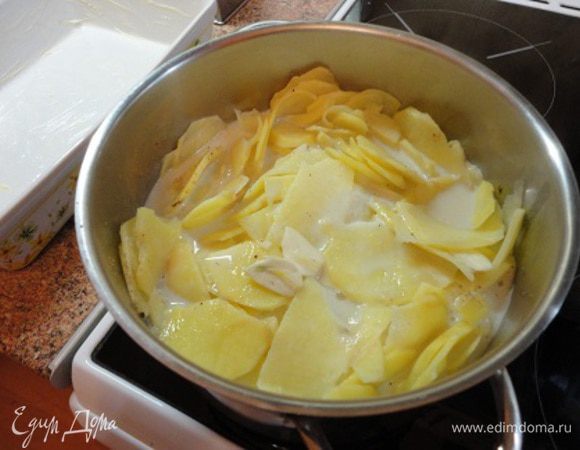 2.	Нарезанный картофель выложить в широкий сотейник с высокими бортиками или кастрюлю, добавить молоко и чеснок (1 половинку оставить). На медленном огне довести до кипения, убавить нагрев и готовить 3 минуты. Добавить мускат, соль, перец.
