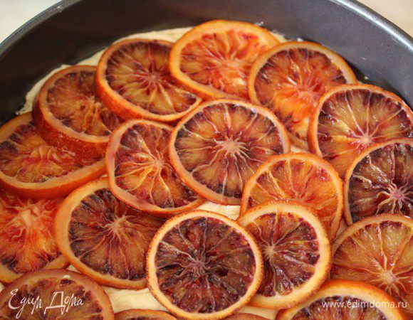 Выложить тесто в выстеленную пергаментом форму и разровнять. Выложить по всей поверхности кольца апельсинов. Выпекать в предварительно разогретой до 200 градусов духовке 15 минут. Затем снизить Т до 175 градусов и печь еще 30 минут. Готовность проверять при помощи деревянной шпажки. 