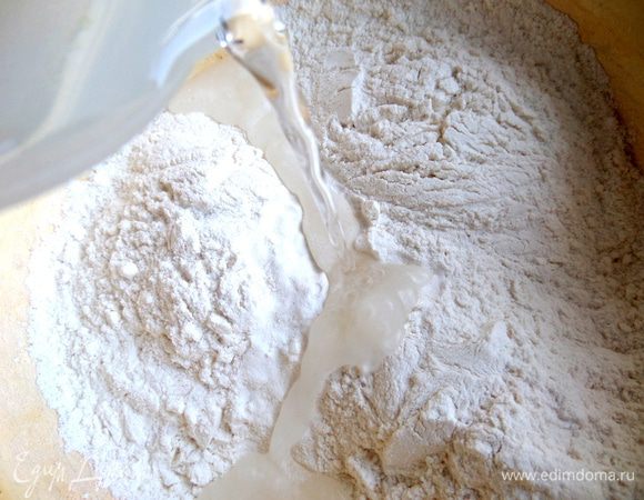 Готовим пельменное тесто. В муку вливаем воду.