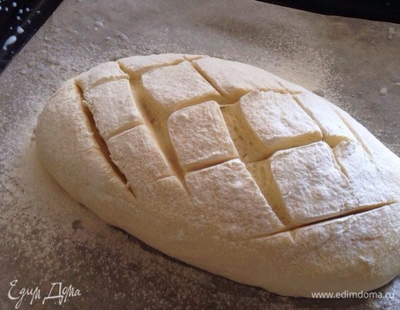 Присыпать мукой и сделать надрезы. Выпекать батон в разогретой до 200 градусов духовке 20-25 минут.