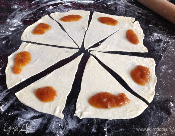 Разделить тесто на 5 частей. Раскатать 1 часть теста на присыпанном мукой столе, разделить на 8 частей, на каждую выложить по одной чайной ложке варенья и закрутить. Также поступить с остальными частями.