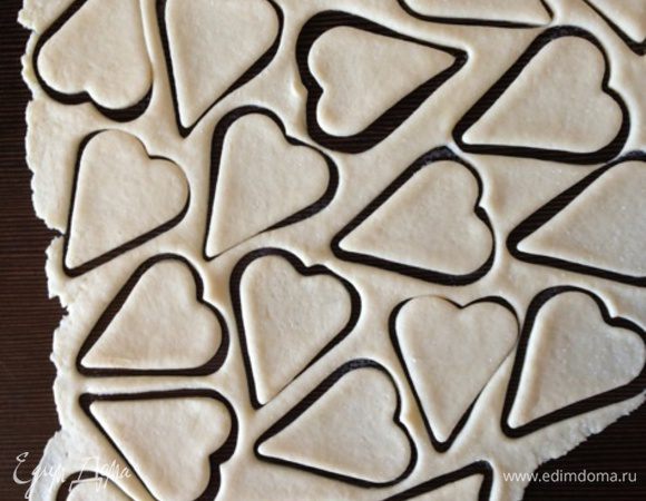 Оставшееся тесто тонко раскатать и вырезать формочкой сердечки. Выложить фигурки поверх карамелек. 