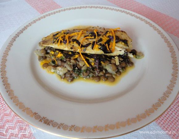 В небольшой сковороде на 1 ст. ложке оливкового масла обжарьте лук до золотистого цвета, перемешайте с чечевицей, добавьте рубленую зелень петрушки и половину соуса. Перемешайте.
Подавайте блюдо, выложив кусочки рыбы поверх чечевицы. Полейте оставшимся соусом, украсьте цедрой.