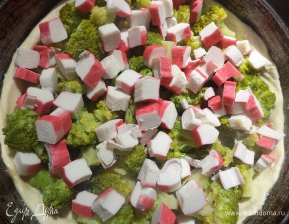  На пласт теста выложить остывшую брокколи, крабовые палочки. Залить всё яично - молочно - сливочной заливкой. 