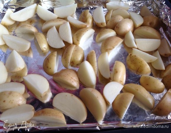 Духовку нагреть до 180 градусов. Картофель вымыть щеткой, разрезать на 4 части, выложить в глубокий противень застеленный фольгой.