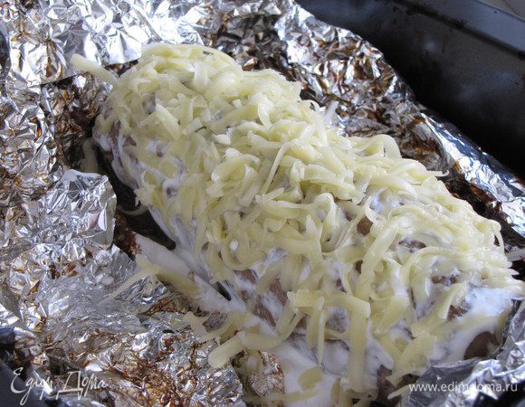 Затем снова достать баклажан из духовки, смазать сметаной, посыпать тертым сыром.