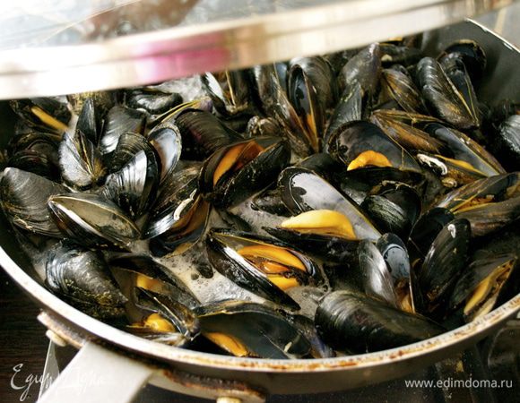 В большую сковороду выложить мидии и, добавив белое сухое вино, поставить на огонь, накрыть крышкой и дать раковинам открыться! Пару раз встряхнуть слегка сковороду (осторожно), чтобы мидии перемешались между собой.