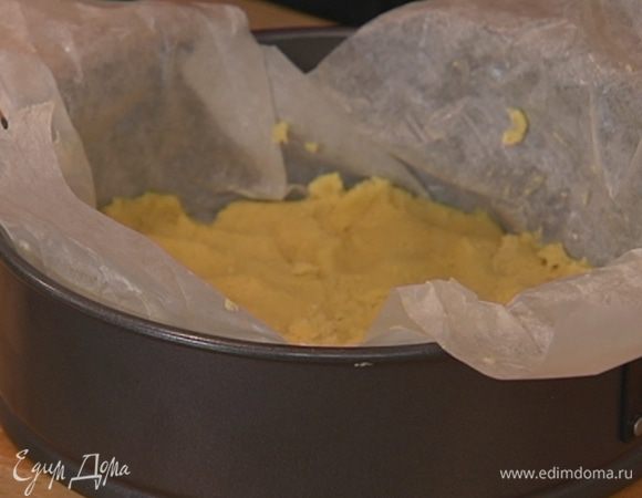 Разъемную форму для выпечки выстелить пищевой бумагой, смазать ее оставшимся сливочным маслом, выложить чуть больше половины теста и сформировать корж толщиной в 1 см.