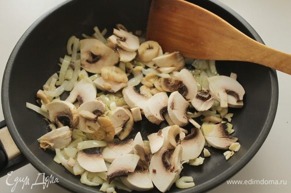 Лук и чеснок очистить и нарезать, обжарить на сковороде в оливковом масле 2-3 минуты,добавить половину грибов.