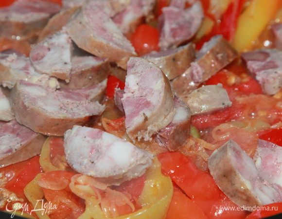 Как только вся эта прелесть даст сок, добавляем порезанный болгарский перец. Перемешиваем, накрываем крышкой и даем всему осесть, затем крышку открываем и, помешивая, тушим на сильном огне практически до полного выпаривания жидкости. Режем колбасу и отправляем к овощам.