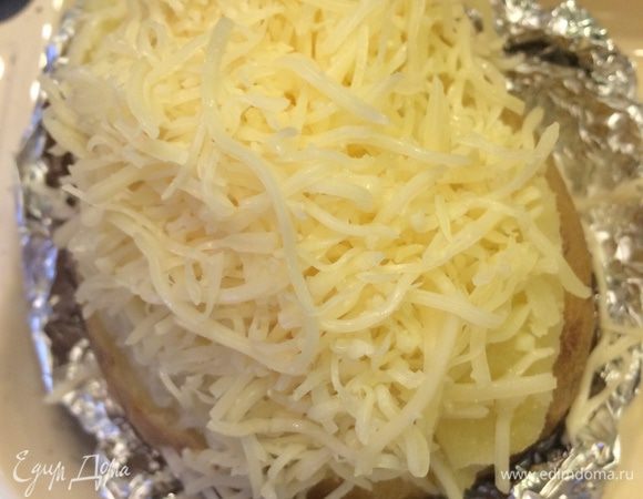 Готовый картофель надрезаем не до конца пополам, немного раздвигаем в стороны половинки, так чтобы они не развалились.
В середину кладем кусочек сливочного масла, солим и посыпаем сыром. 
Отправляем в духовку по гриль, чтобы появилась румяная корочка. 