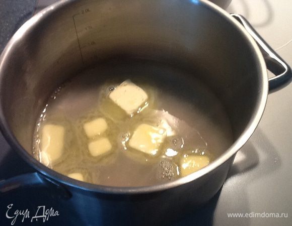 В кастрюлю положить порезанное масло, добавить соль, влить горячую воду, поставить на огонь.