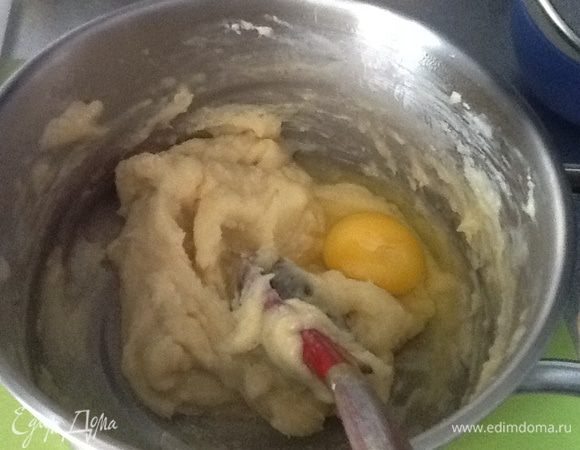 Как только масло растает и вода закипит добавляем муку и сразу снимаем с огня. Взбиваем тесто деревянной ложкой, добавляем ванильный экстракт, затем желток, далее по одному яйца. Перемешиваем тесто до гладкости.
