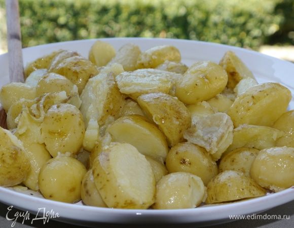 Готовый картофель выложить на блюдо, полить маслом, в котором он запекался, и подавать с салатом.