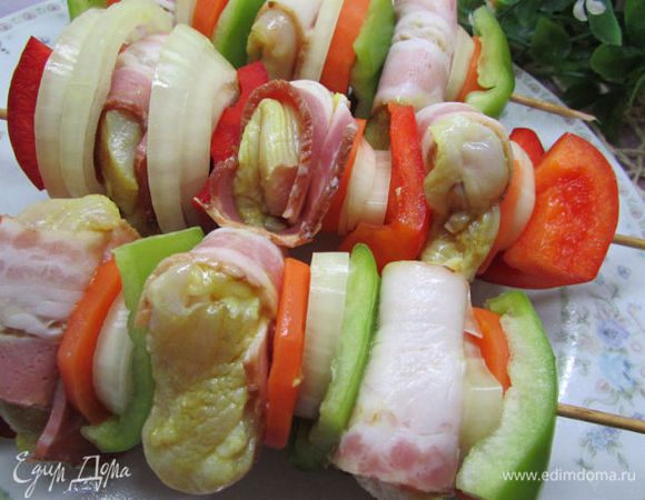 Каждый кусочек обернуть беконом. На каждый шампур наколоть 3 кусочка мяса, чередуя с овощами.