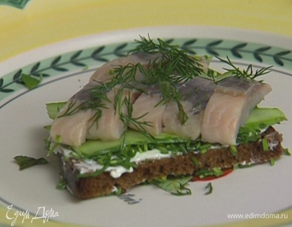 На каждый кусок хлеба положить по 3 кусочка огурца, 3–4 кусочка сельди, присыпать зеленью.