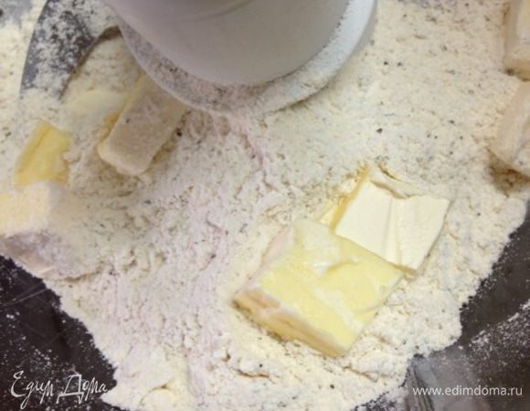 Добавим нарезанное маленькими кусочками масло и смешаем до состояния сухой крошки. Лучше всего это делать при помощи кухонной техники с насадкой-ножом.