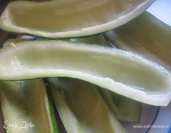 Огурцы лучше взять большие, их удобнее начинять. Срезать у огурцов конец со стеблем, разрезать вдоль и чайной ложкой выбрать сердцевину.