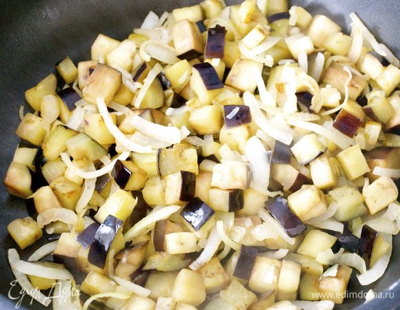 Разогреть масло в большой сковороде и поджарить баклажаны и лук  в течение 10 минут. 