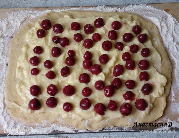 Берем банку консервированной вишни 370мл. Вишню опрокинуть на сито и дать стечь соку. Дрожжевое тесто руками немного размять и раскатать на посыпанной мукой поверхности прямоугольной формы 24*30. Пудинг размешать и выложить на тесто, оставляя 2см по краям. Распределить равномерно вишню.