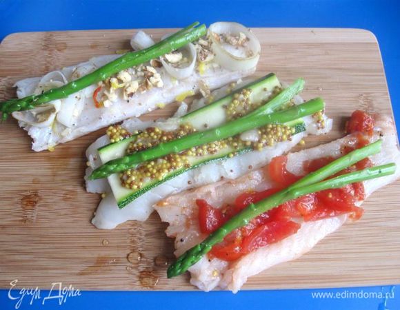 На кусочек трески с лимонным маринадом положить немного  лука – порея, измельченных грецких орехов, вдоль положить стебелек спаржи. На кусочек трески, который  мариновался с дижонской горчицей и чесноком, положим слайд цукини и веточку спаржи. На третий кусок трески выложить кусочки помидора из маринада, вдоль положить веточку спаржи.