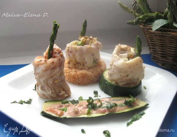 Сварить кус- кус с добавлением небольшого количества воды и пассированных томатов. Посолить. После остывания через кольцо оформить в виде невысокого цилиндра  кус – кус. Другой цилиндр на тарелке – кружок цукини. На тот и другой поставить рулеты из трески ( если необходимо, подрезать для устойчивости нижнюю часть трески). Третий рулет поместить без дополнительных компонентов в основании.
