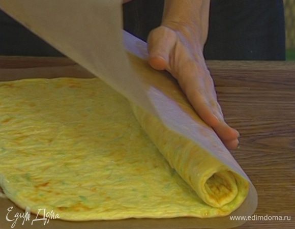 Снять бумагу и свернуть тесто в рулет.