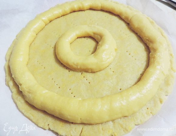 Раскатываем тесто в круг диаметром 24-25см. Сверху при помощи кондитерского мешка с большой круглой насадкой выдавливаем два кольца из заварного теста. Остальное тесто отсаживаем в виде небольших круглых пироженок. 
