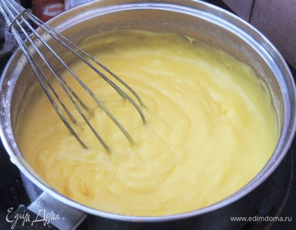 Теперь вливаем к желтковой массе теплое молоко и отправляем на плиту. Доводим крем до кипения на среднем огне, постоянно помешивая. Как только крем загустеет и начнет булькать - он готов. Перекладываем крем в большую кастрюльку, накрываем его пленкой в контакте с поверхностью крема и отправляем на холодную баню остывать.