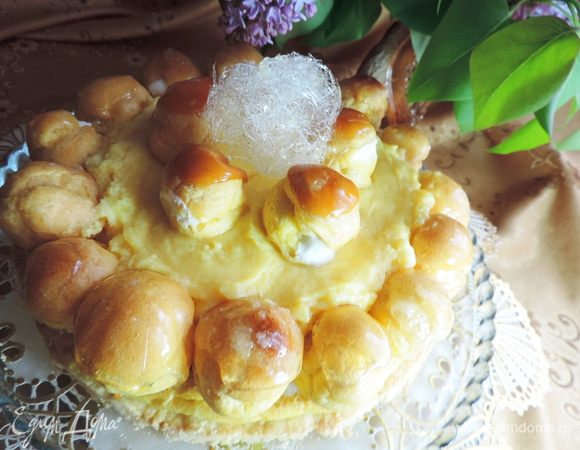 Когда все кольцо будет заполнено пирожными, выливаем в центр заготовки заварной крем, который уже загустел и начал застывать. Теперь торт должен часок-другой провести в холодильнике. Украшать торт нужно непосредственно перед подачей к столу, поскольку карамельные украшения мгновенно тают в холодильнике. Я украсила торт оставшимися пирожными и шариком из карамельных нитей. Можно вместо шарика украсить торт карамельными нитями. 