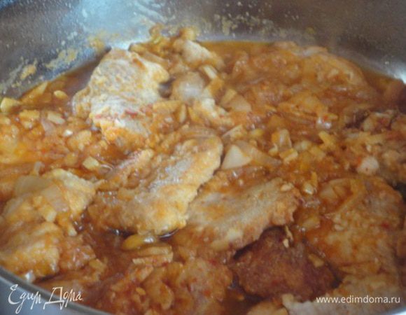 4.	Лук и чеснок мелко нашинковать (я нарезала лук тонкими полукольцами) и обжаривать в том же масле, где жарилось мясо, вначале лук до золотистости, затем добавить чеснок, томатный соус (я добавила острый кетчуп), уксус (я использовала яблочный), сахар, соль, и острый красный перец. В рецепте его не было вообще. Мне показался он там очень даже нужным, и я не ошиблась. Влить полстакана горячей воды. Дать покипеть пару минут  и выложить кусочки мяса. Продолжить готовить на медленном огне до готовности мяса.