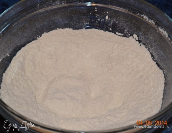 В миске смешать муку, сахар и соль и высыпать на рабочую поверхность или большую  доску для резки.