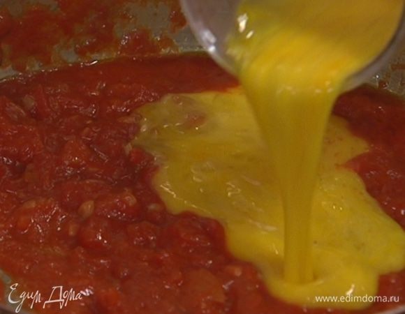 Яйца слегка взбить, посолить, поперчить и вылить в сковороду с луком и помидорами.