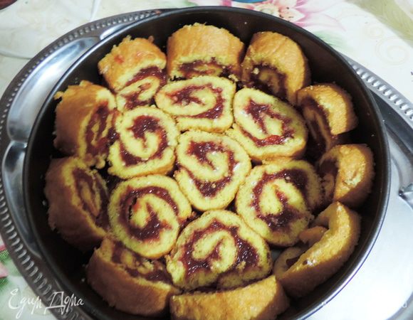 Охлажденный рулет нарезаем острым ножом на кусочки примерно 0,7-0,8см. На блюдо кладем кулинарное кольцо или бортик от разъемной формы диаметром 23-24см. Выкладываем дно и бока формы кусочками рулета.