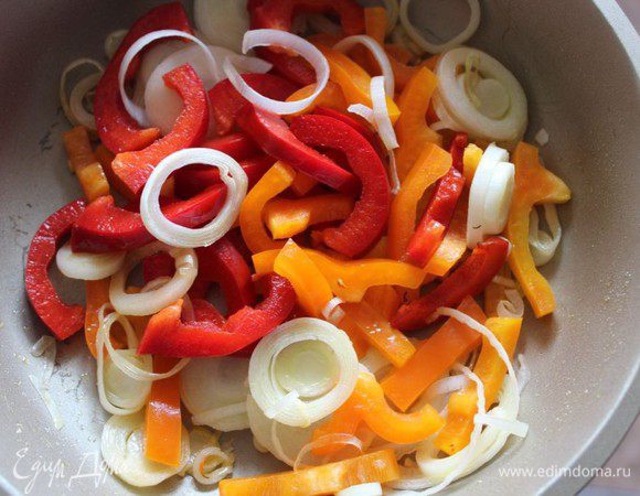 Порей (белую часть) нарезать тонкими полукольцами, болгарские перцы (у меня красный и оранжевый) нашинковать средними полосками. На оливковом масле обжарить овощи в течение 5 минут.