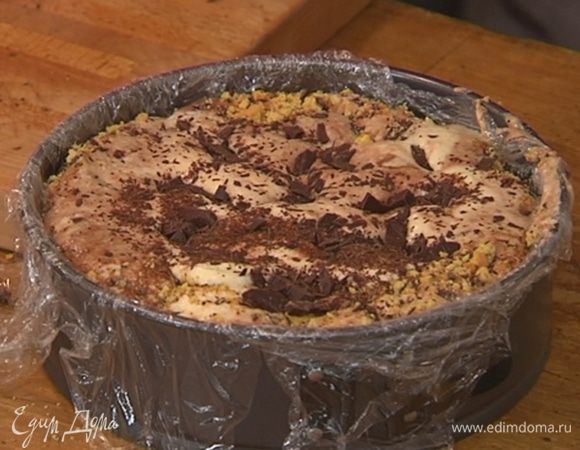 На дно формы равномерным слоем высыпать часть измельченного печенья, сверху вылить половину крема, посыпать частью шоколадной крошки и оставшимся печеньем.