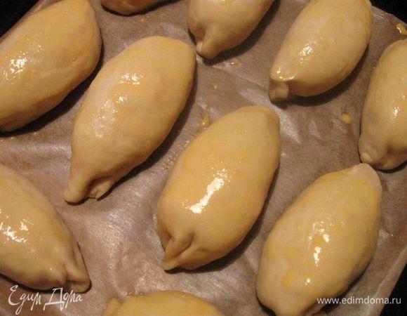  Каждый шарик раскатать  в пласт. Выложить  начинку и защипнуть  края.
Выложить  пирожки на противень, застеленный  бумагой для выпечки, смазать кисточкой  их поверхность  желтком, разбавленным молоком. 