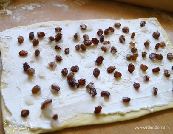 Смазать слоем сыра творожного и разложить изюм в сахаре.