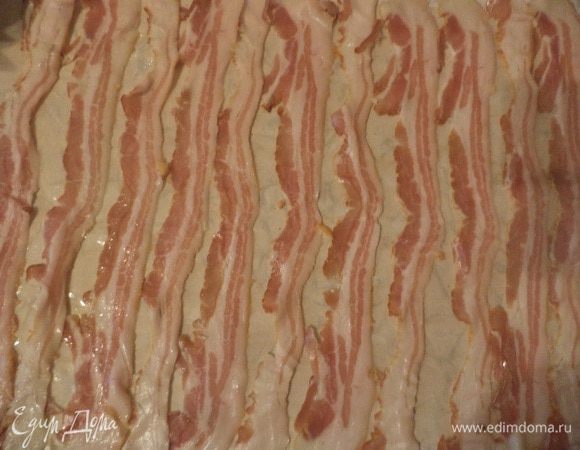 Лист бумаги для выпечки смазать растительным маслом, на лист бумаги выложить полоски бекона вплотную друг к другу, сверху в виде пласта выложить мясной фарш.