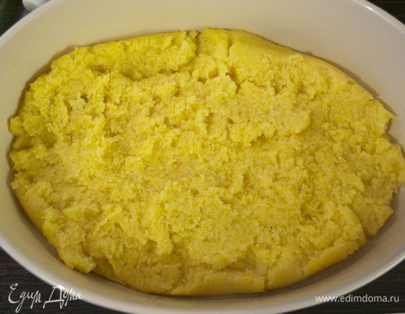 Затем выложить поленту в смазанное жиром огнеупорное блюдо, выровнять поверхность и выпекать в духовке 25 минут.