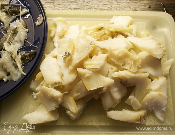 За это время треску вынуть из воды, в которой она варилась, дать воде стечь, очистить от костей и кожи, расслоить рыбу. Тоже проделать с анчоусами, порезать их.